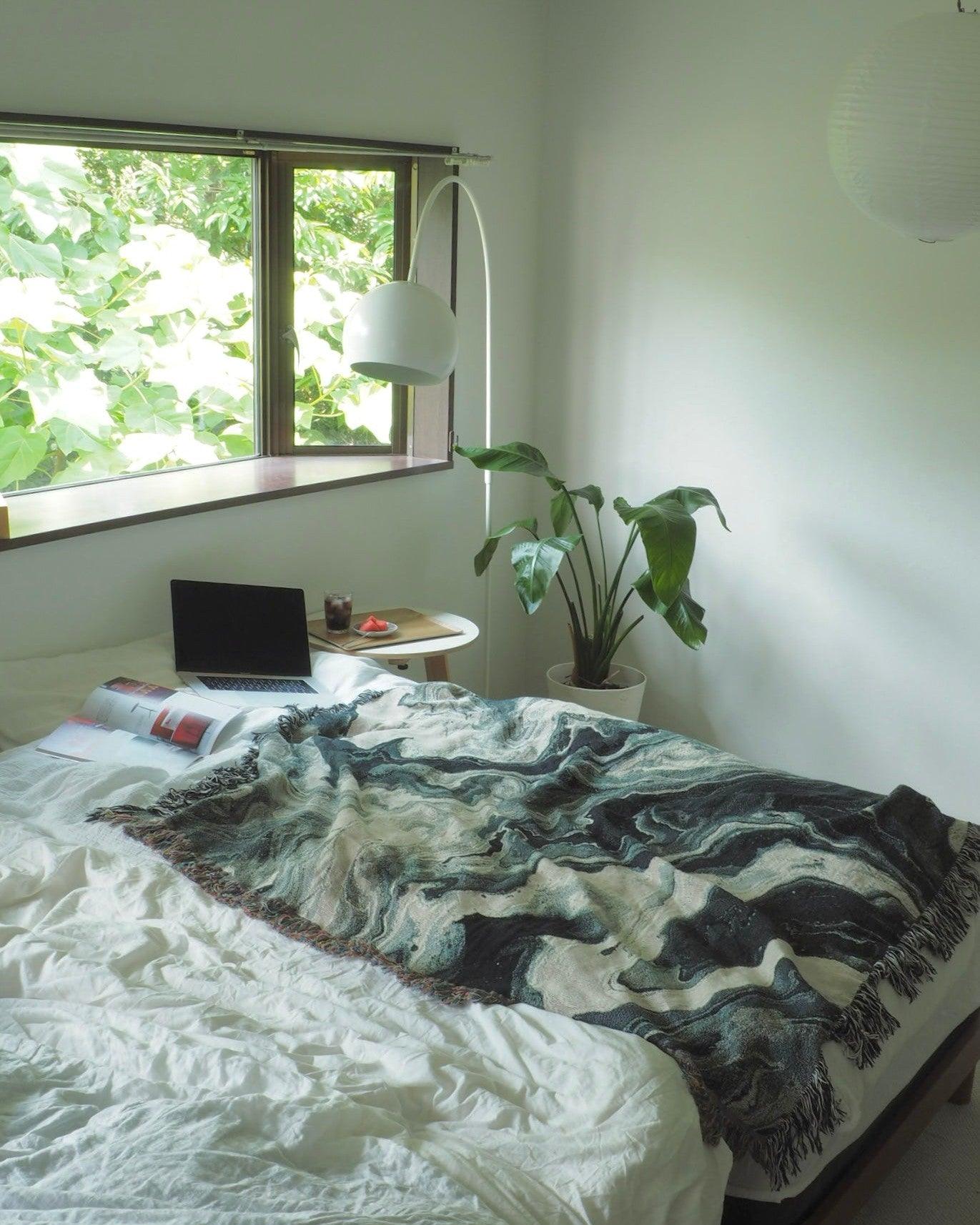 明るい寝室のベッドに広げられたBlack Flow Throw Blanket